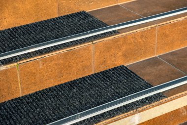 Verandadaki merdivenleri kaplayan seramik karoların üzerinde lastik kaygan çizgiler var..