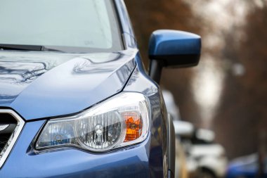 Şehrin cadde tarafında park edilmiş yeni temiz arabanın ön farının önü..