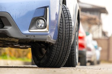 Yeni kış lastikleriyle şehir sokaklarında park halindeki bir araca yaklaş..