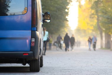 Yolcu minibüsü, sonbaharda bulanık yürüyen yayalarla şehir caddesi kenarına park edilmiş..