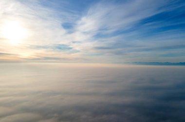 Parlak güneşli bir günde, beyaz kabarık bulutların yukarıdan görünüşü.