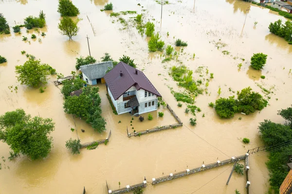 Aerial view of flooded house with dirty water all around it.