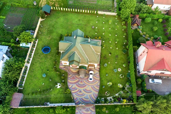 Aerial top view of house shingle roof and a car on paved yard with green grass lawn.
