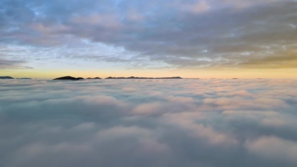 水平線に遠くの暗い山と白い高密度の雲の上の活気のある夕日の空中ビュー — ストック動画