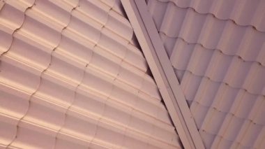 Kahverengi metal kiremitlerle kaplı evin çatı yapısının havadan görünüşü.