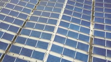 Sanayi binasının çatısına monte edilmiş mavi fotovoltaik panelleri olan güneş enerjisi santralinin hava görüntüsü.