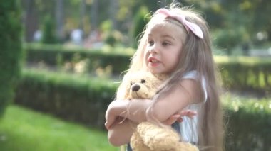Mutlu küçük kız, en sevdiği oyuncak ayısıyla yaz parkında oynuyor..