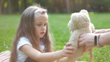 Mutlu çocuk oyuncak ayısıyla oynuyor yaz parkında yeşil çimlerde oturuyor.