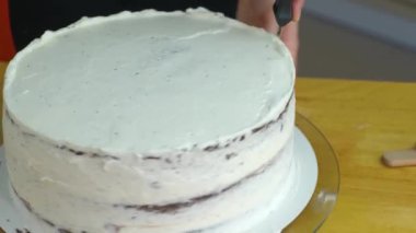 Kadın ellerine yakın beyaz krema ve bisküviyle tatlı pasta yapıyor..