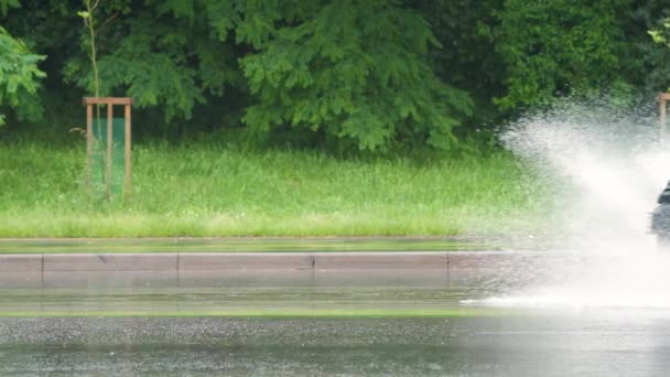 汚れた雨の水で浸水した道路に噴霧を残して高速運転車 — ストック動画