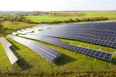 Yeşil alanda inşa halindeki güneş enerjisi santralinin havadan görüntüsü. Temiz ekolojik enerji üretmek için elektrik panellerinin montajı.