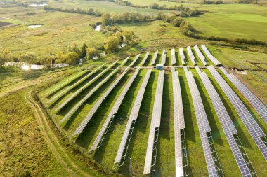 Yeşil alanda inşa halindeki güneş enerjisi santralinin havadan görüntüsü. Temiz ekolojik enerji üretmek için elektrik panellerinin montajı.