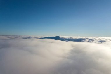 Beyaz kabarık bulutların ve parlak güneşli bir günde uzak dağın tepesinden gökyüzü manzarası.