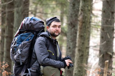 Sırt çantalı fotoğrafçı dijital fotoğraf makinesiyle doğanın fotoğraflarını çekiyor..