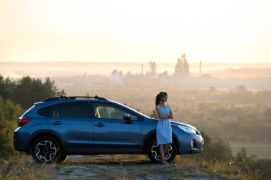 Mavi elbiseli mutlu genç kadın şoför sıcak yaz gününün tadını çıkarıyor. Seyahat ve tatil kavramı.