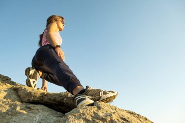 Güneşli bir günde kadın yürüyüşçü dik kayalara tırmanıyor. Genç bayan dağcı zor tırmanma rotasının üstesinden gelir. Doğada aktif eğlence kavramı.