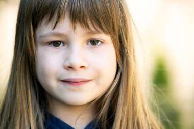 Gri gözlü, açık havada açık havada açık yeşil arka planda uzun sarı saçlı güzel bir kızın portresi. Sıcak yaz gününde tatlı bir bayan çocuk..