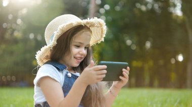 Mutlu gülümseyen kız yazın açık havada cep telefonuna bakıyor..