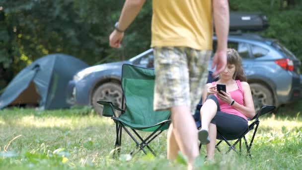 若いカップル座ってキャンプ場の近くで幸せに一緒に話す — ストック動画