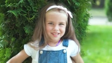 Yaz parkında durup kameraya bakıp mutlu gülümseyen güzel bir kızın portresi..