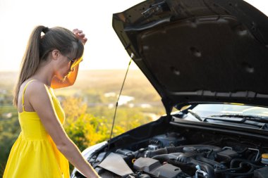 Kaputu patlamış, arabasının yanında duran genç kadın sürücünün motor sorunları var..