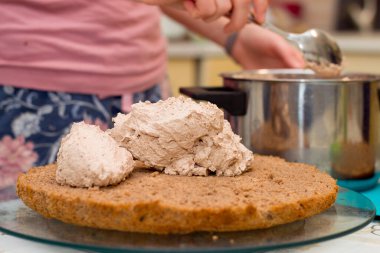 Evde kek pişirme süreci. Çikolatalı bisküvinin üzerine kadın el kreması dök. Mutfak ve lezzetli tatlı konsepti.