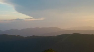 Rüzgarlı bir akşamda uzak yeşil dağ tepelerinin panoramik manzarası.