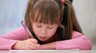 Güzel kız bir odada yere bir kağıt parçası yazıyor..