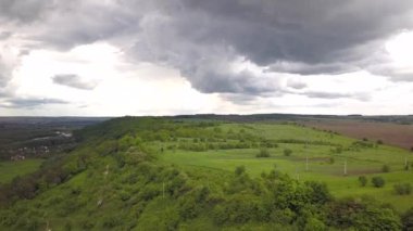 Ormanlı yeşil tepelerin ve yazın kara yağmur bulutlarının havadan görünüşü..