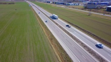 Yeşil tarlalar arasında hareket halindeki arabalarla çevre yolu.