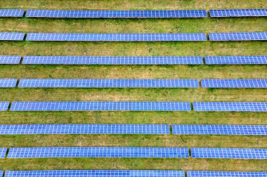 Yeşil alandaki güneş enerjisi santralinin havadan görüntüsü. Temiz ekolojik enerji üretmek için panelleri olan elektrik çiftliği.