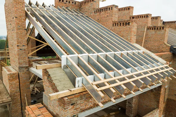 Aerial view of unfinished brick apartment building with wooden roof structure under construction.