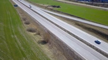 Yeşil tarlalar arasında hareket halindeki arabalarla çevre yolu.