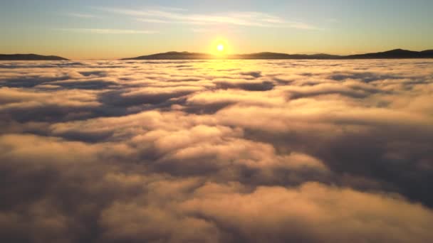 水平線に白い高密度の雲と遠くの山の上の鮮やかな黄色の日の出の空中ビュー — ストック動画