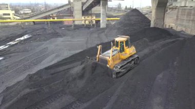 Buldozer çekici termoelektrik santralinin ikmal sahasında siyah kömür topluyor..
