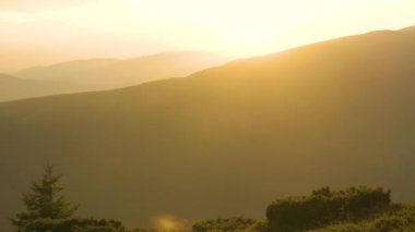 Rüzgarlı bir akşamda uzak yeşil dağ tepelerinin panoramik manzarası.
