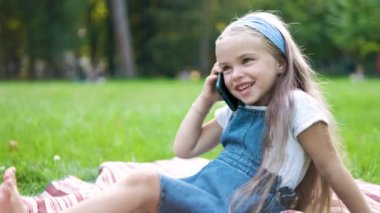 Mutlu küçük kız, yaz parkında cep telefonuyla konuşuyor..