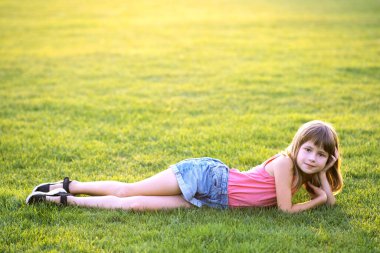 Genç ve güzel bir kız sıcak yaz gününde yeşil çimlere uzanıyor..