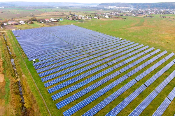 Aerial view of solar power plant on green field. Electric farm with panels for producing clean ecologic energy.