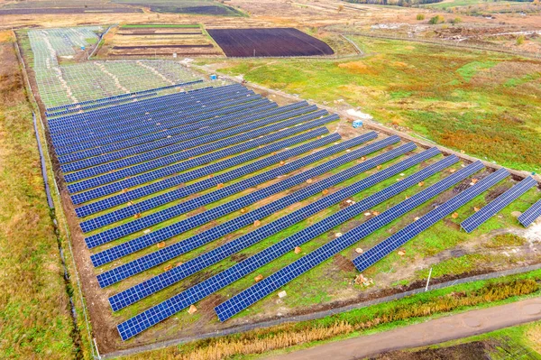 Aerial view of solar power plant under construction on green field. Assembling of electric panels for clean ecologic energy production.