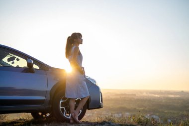 Mavi elbiseli mutlu genç kadın şoför sıcak yaz gününün tadını çıkarıyor. Seyahat ve tatil kavramı.