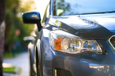 Şehrin cadde tarafında park edilmiş yeni temiz arabanın ön farının önü..