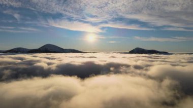 Ufuktaki Karpat dağlarının uzak karanlık zirveleriyle beyaz yoğun sis üzerinde canlı gün doğumunun havadan görüntüsü.
