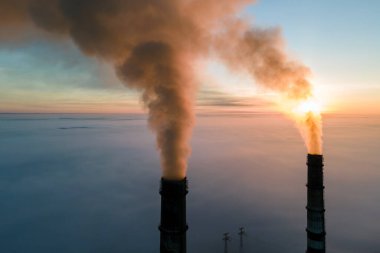 Kömür santralinin hava manzarası siyah dumanlı yüksek borular gün batımında atmosferi kirletiyor.