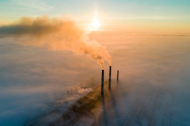 Kömür santralinin hava manzarası siyah dumanlı yüksek borular gün batımında atmosferi kirletiyor.