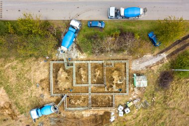 Kırsal yerleşim alanındaki yeni ev beton temeli inşaatlarının havadan aşağı manzarası.