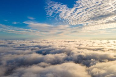 Parlak güneşli bir günde, beyaz kabarık bulutların yukarıdan görünüşü.