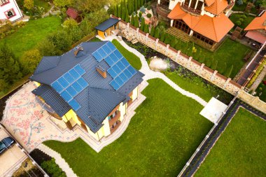 Çatıda temiz elektrik üretmek için güneş fotovoltaik panelleri olan özel bir evin havadan görüntüsü. Özerk konut kavramı.