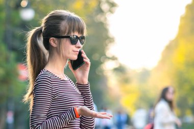 Sıcak yaz gününde cep telefonuyla konuşan genç ve güzel bir kadın..