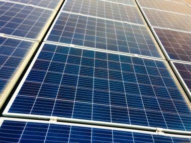 Temiz ekolojik elektrik üretmek için çatıya monte edilen mavi fotovoltaik güneş panellerinin havadan görünüşü. Yenilenebilir enerji konsepti üretimi.